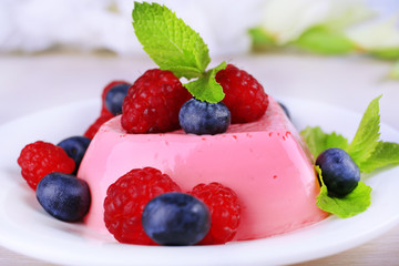 Heart shaped cake with berries on plate on wooden background