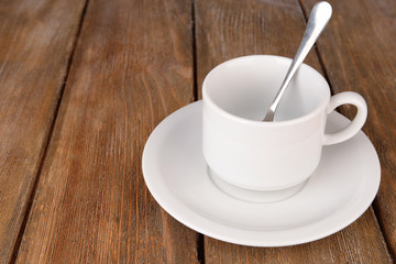 Empty cup with tea spoon on wooden background