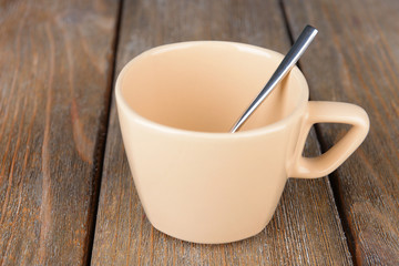 Empty cup with tea spoon on wooden background