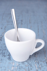 Empty cup with tea spoon on wooden background