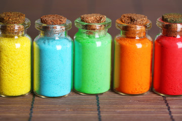 Bottles with colorful dry pigments on bamboo mat background