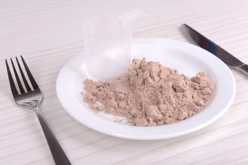 Whey protein powder on plate with scoop on wooden background