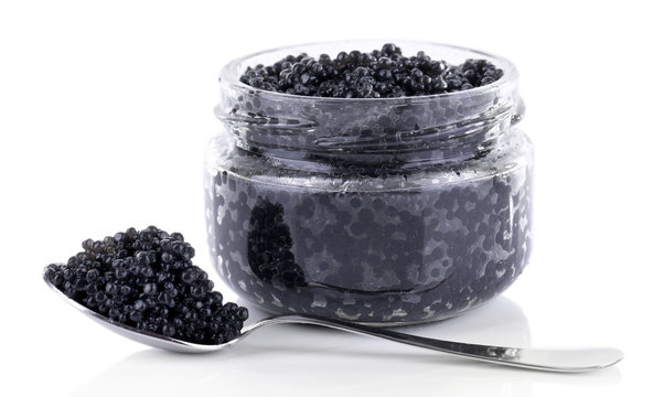 Glass jar and spoon of black caviar isolated on white