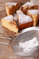 Pieces of delicious cake on cutting board on wooden table