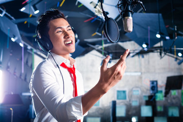 Asian male singer producing song in recording studio