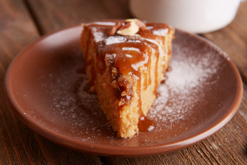 Piece of delicious cake on plate on wooden table