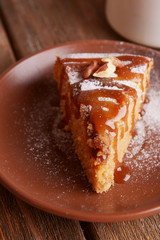 Piece of delicious cake on plate on wooden table