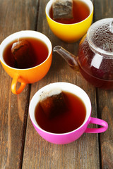 Cups of tea, teapot and tea bags on wooden table close-up