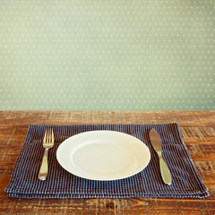 White plate on tablecloth over vinatge background