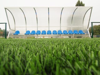 Empty blue plastic seats on outdoor stadium players  bench,
