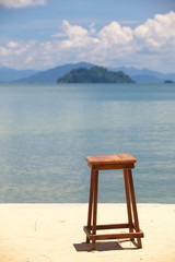 wooden chair on nice sand beach with sea in background