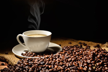 Coffee cup and coffee beans with smoke on burlap sack