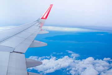 Wing of airplane flying above the clouds in the sky