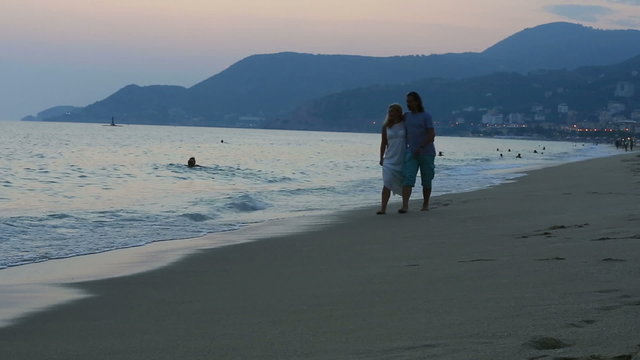 happy couple walking on the beach together at sunset