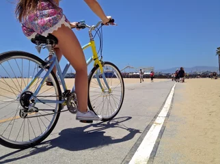 Fototapeten Pretty Woman riding a bicycle along Santa Monica Beach pathway © samantoniophoto