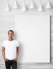 Man wearing blank t-shirt and white poster on a wall