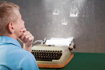 Cute little boy typing on retro typewriter