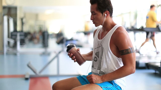attractive young man drinking energy drink during a break at gym