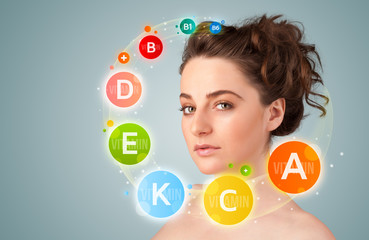 Pretty young girl with colorful vitamin icons and symbols