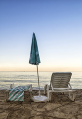 Chairs and umbrella on a beach at sunrise