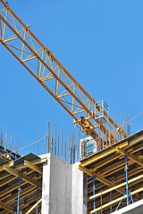 Crane and building construction site against blue sky