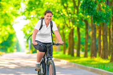 Joyful girl on a bicycle with a backpack