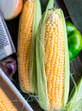 raw yellow corn on the cob on a green wooden background,closeup