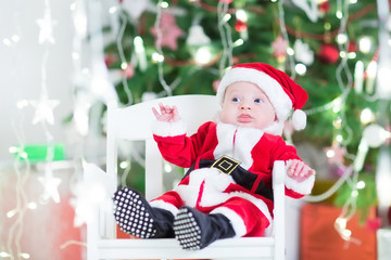 Adorable newborn baby boy in Sante outfit sitting in a white cha
