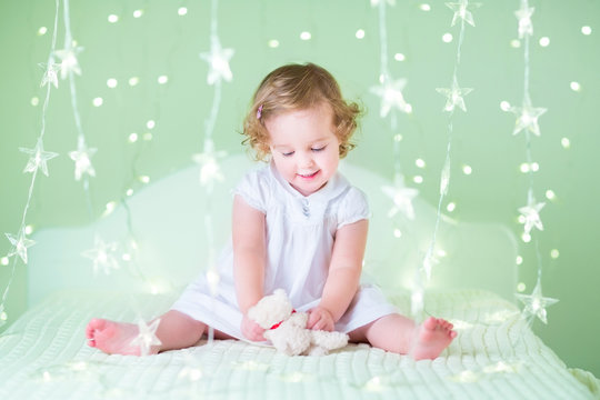 Sweet toddler girl playing with her bear toy sitting between bea