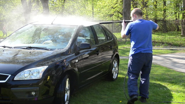 Worker wash black car outdoor with high pressure water equipment