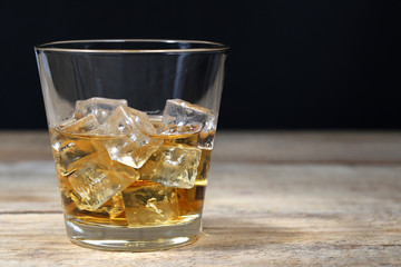 Whisky im Glas mit Eiswürfeln auf Holzbrett