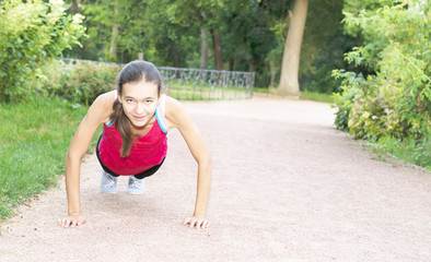 young woman doing push-ups in the park