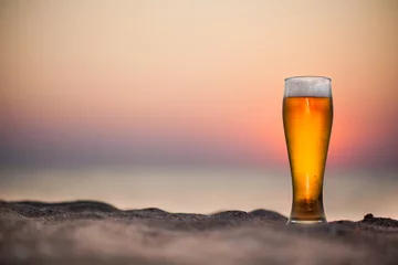 Zelfklevend Fotobehang Glass of beer on a sunset © merydolla