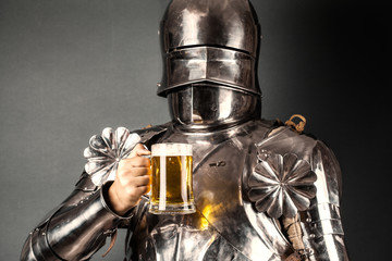 knight wearing armor and holding mug of beer - obrazy, fototapety, plakaty