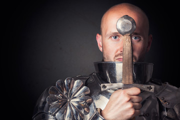 knight wearing armor and holding two-handed sword in front of hi