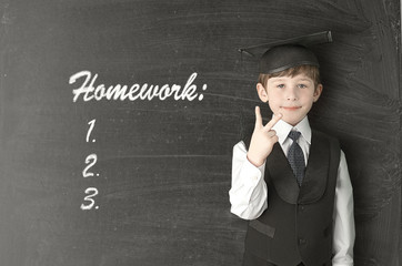 Cheerful little boy on blackboard. Looking at camera