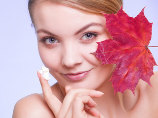 Fototapeta na wymiar Skin care. Face of young woman girl with red maple leaf.