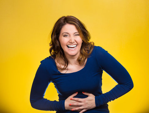 Laughing woman hearing good news, joke on yellow background 
