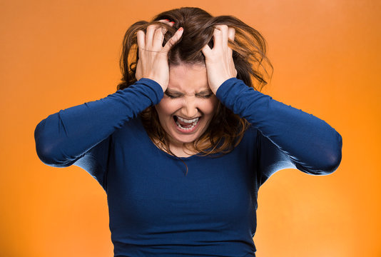 Stressed business woman, pulling her hair out, orange background