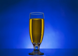 glass withe yellow liquid on blue background