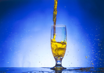 splash glass withe yellow liquid on blue background
