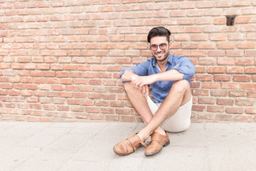 man sitting near brick wall and smiles