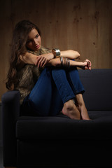 Portrait of elegant woman sitting on black sofa wearing a blue