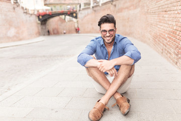 Obraz premium man with glasses sitting on the sidewalk in a city