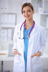 Portrait of young woman doctor with white coat standing in hosp