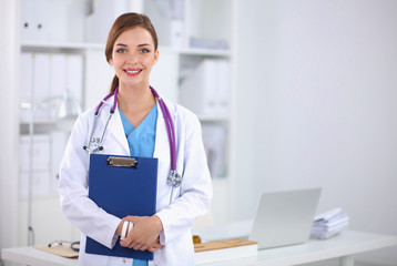 Smiling female doctor with a folder in uniform standing at hosp