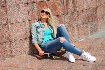 Fototapeta na wymiar trendy girl in jacket sitting on a skateboard 