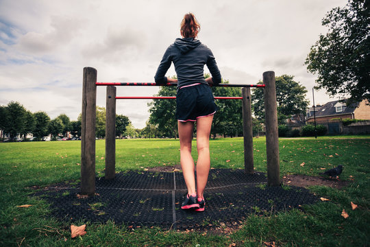 Young woman standing by fitness equipment in the park