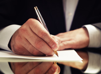 hands of a businessman in a suit signing or writing a document