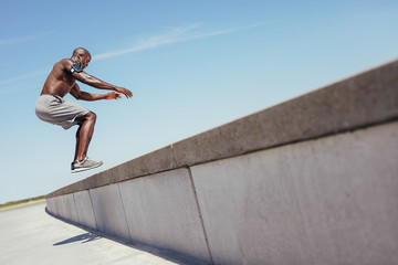 Muscular man doing box jumps outdoors.